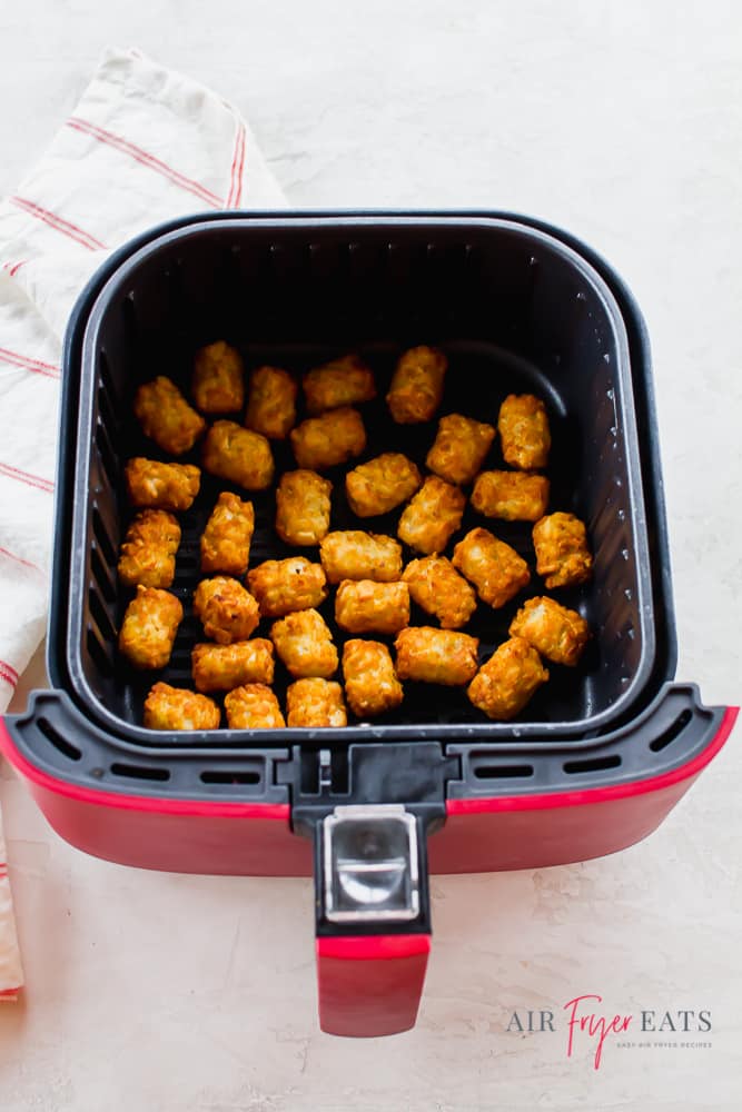 cooked air fryer tator tots in a red air fryer basket