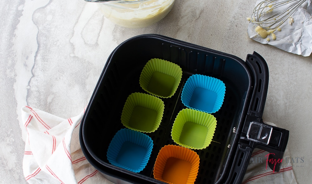 empty cupcake holders in a black air fryer basket
