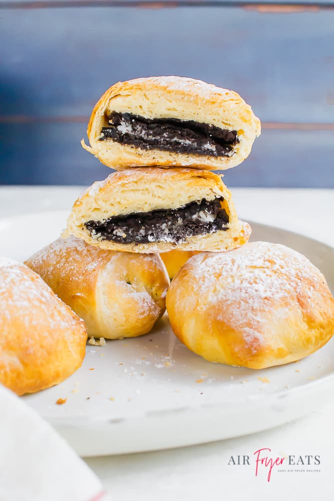 A stack of air fried Oreos on a white plate dusted with powdered sugar