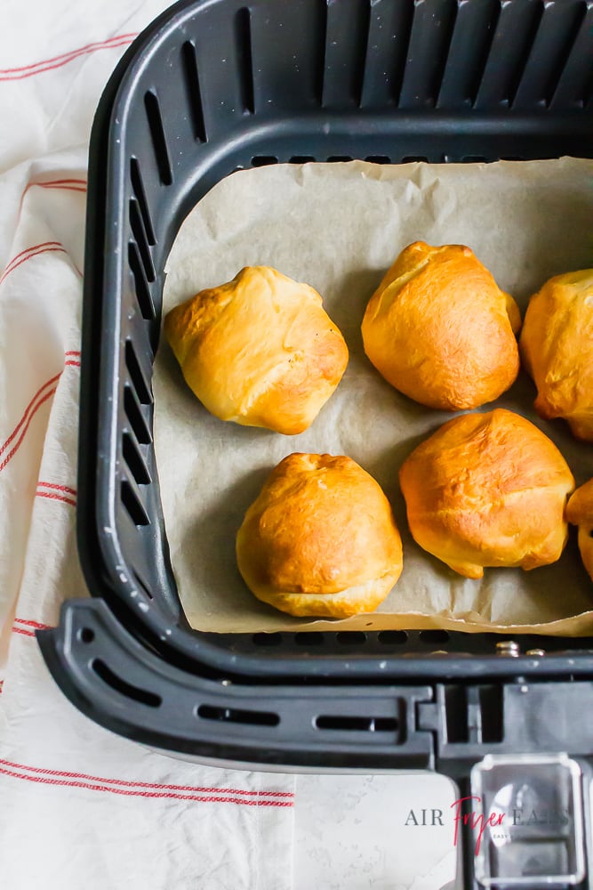 Oreos wrapped in crescent rolls in an air fryer basket with parchment paper