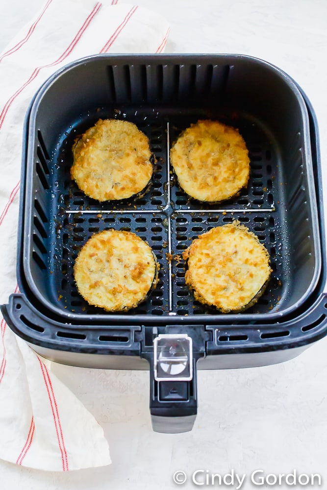 Crispy eggplant slices in an air fryer basket. 