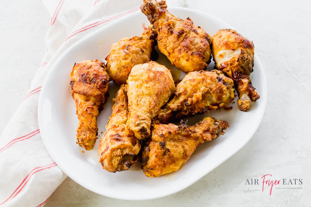 Overhead shot of air fried chicken drumsticks on a white platter