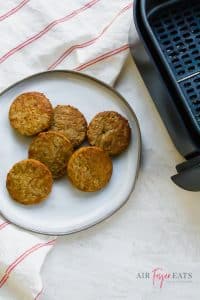 A white plate with 6 breakfast sausages