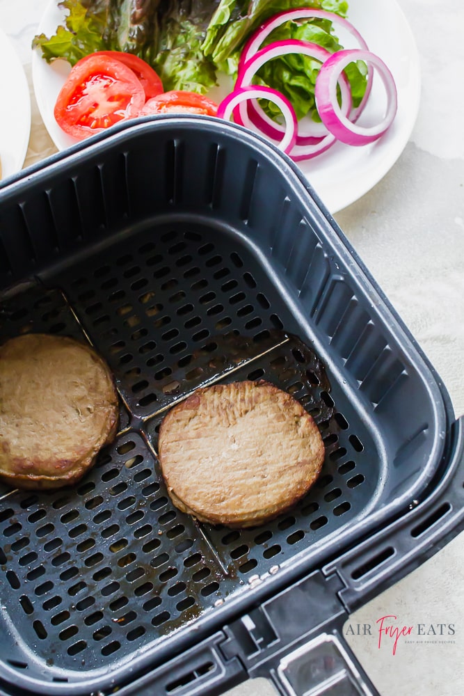 Two turkey burger patties in an air fryer basket