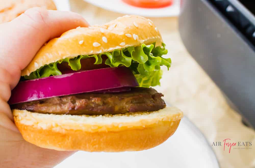 Turkey burger with lettuce, red onion, and tomato on a sesame seed bun