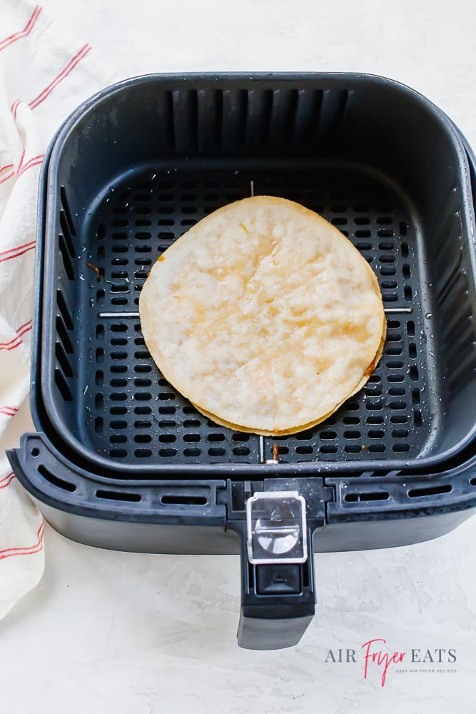 An air fryer basket with a cooked quesadilla inside. 