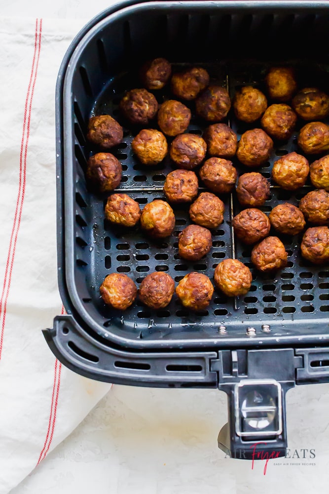 a square air fryer basket full of cooked meatballs.