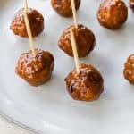 bbq meatballs with toothpicks on a white plate.