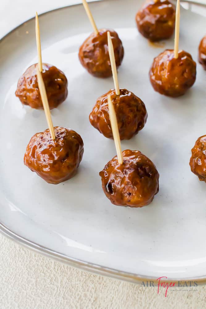 bbq meatballs with toothpicks on a white plate. 