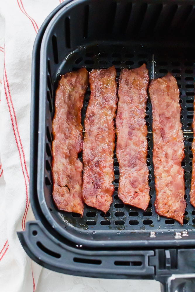 slices of cooked turkey bacon in a square air fryer basket.