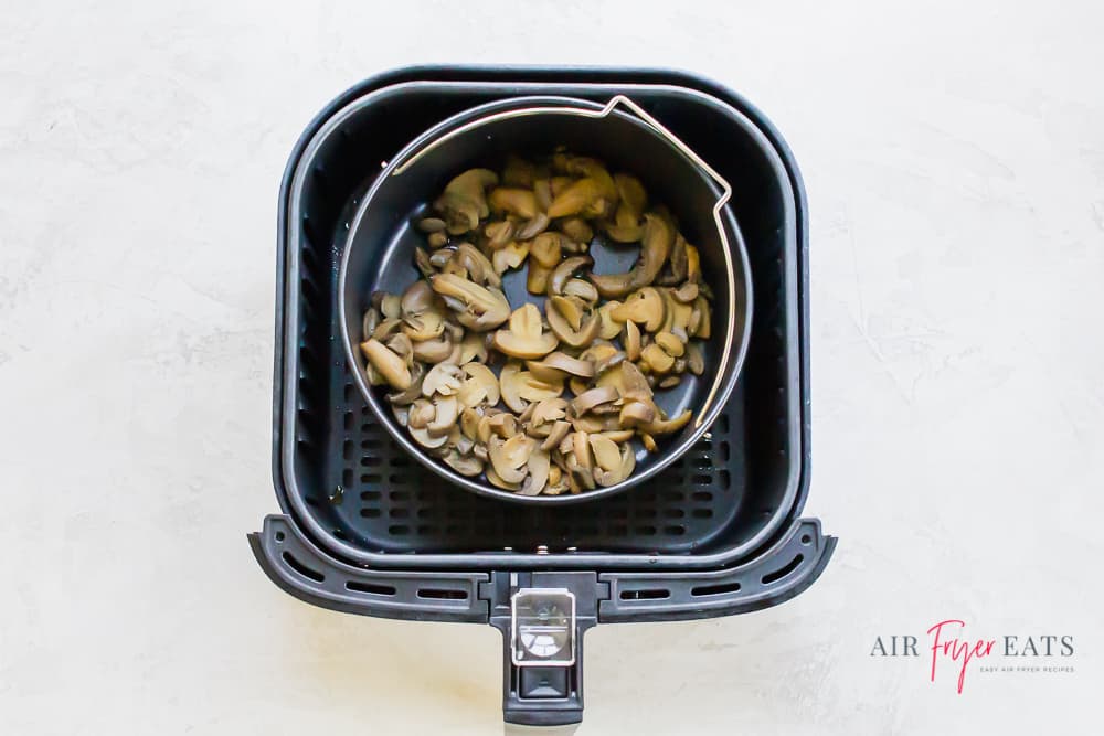 canned mushrooms in an air fryer pot inside of an air fryer basket