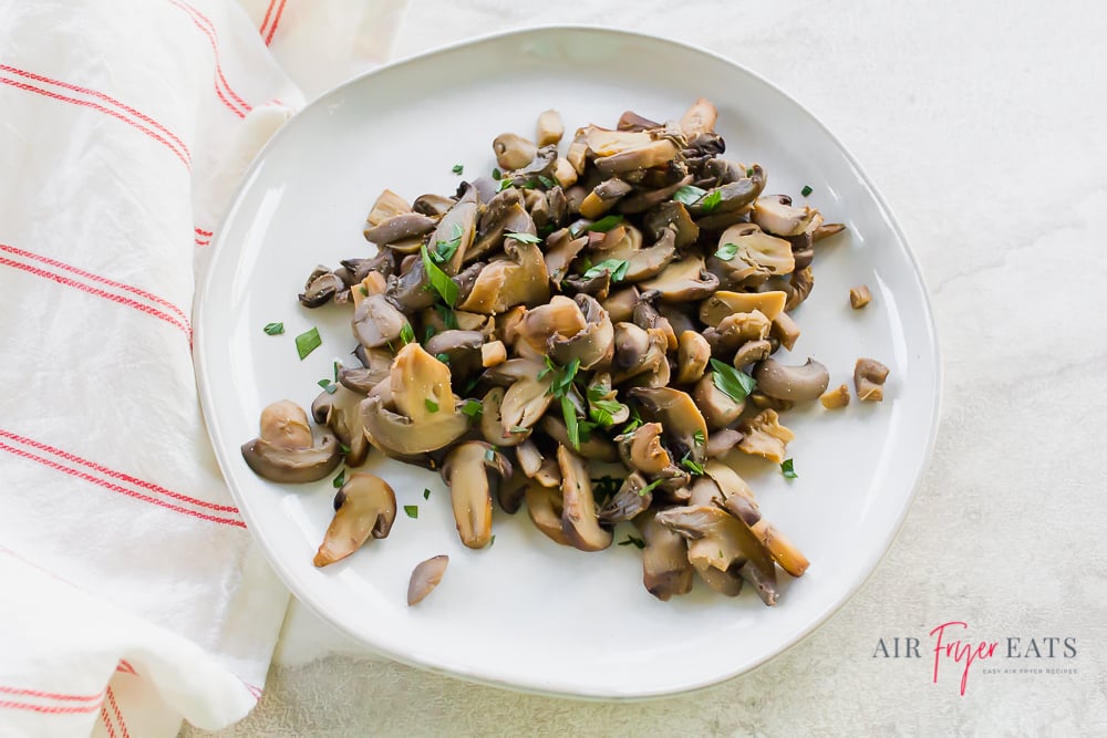 horizontal image of canned air fryer mushrooms on a white plate.
