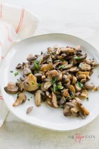 a plate of cooked mushrooms topped with herbs