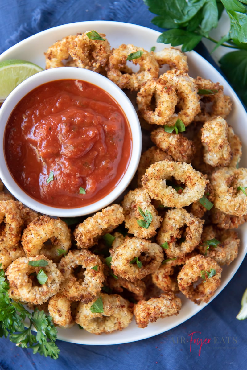 A platter of air fried calamari with a side of marinara sauce