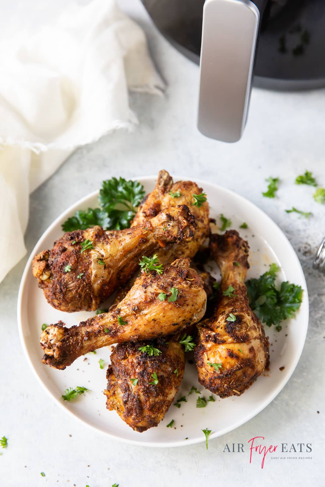 a white plate of chicken legs garnished with parsley.