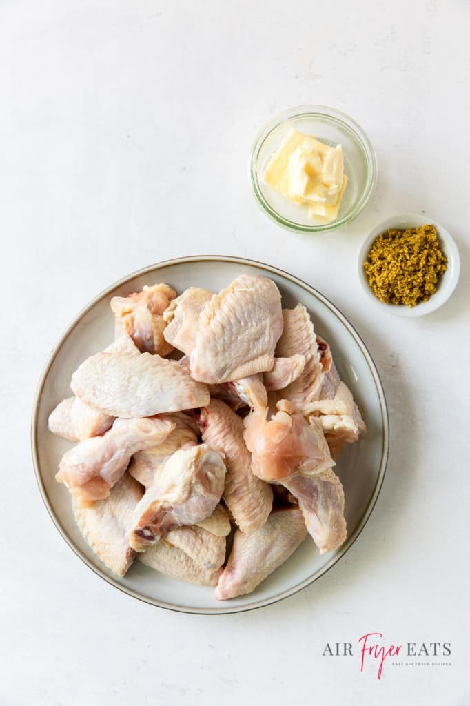 ingredients needed to make lemon pepper chicken wings, including raw chicken wings, spices, and butter