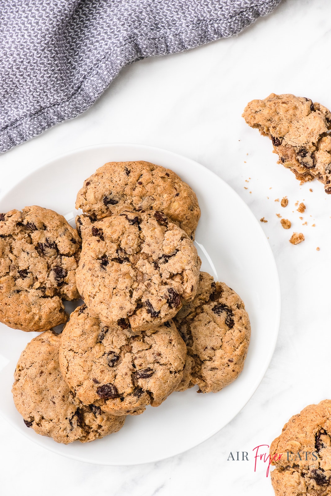 a plate of oatmeal raisin cookies next to a blue kitchen towel.