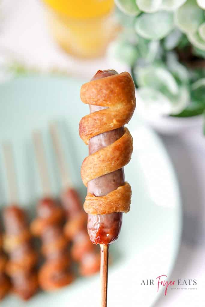a breakfast sausage wrapped in crescent dough on a skewer