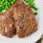 a white scalloped plate with two cube steaks and peas