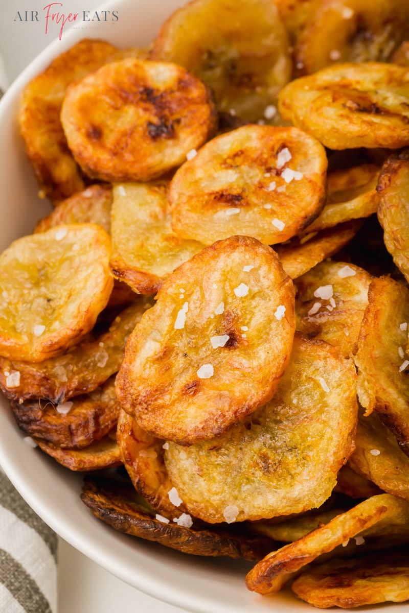 a closeup view of a plate of crispy banana chips with salt.