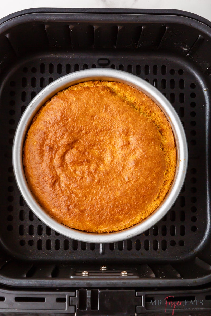 a round metal pan of cornbread inside of a square cosori air fryer basket