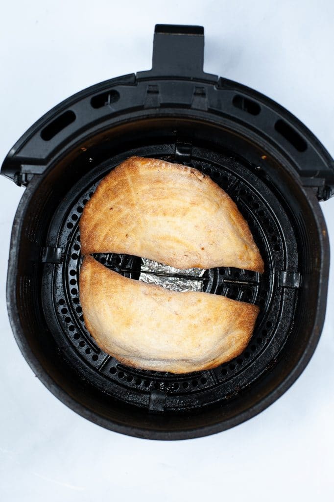 two calzones in a round air fryer basket