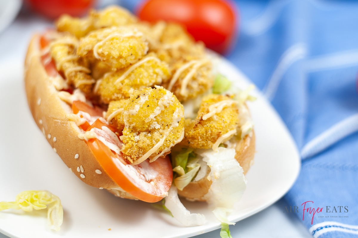 air fryer crispy shrimp po boy on a white plate, garnished with mayo