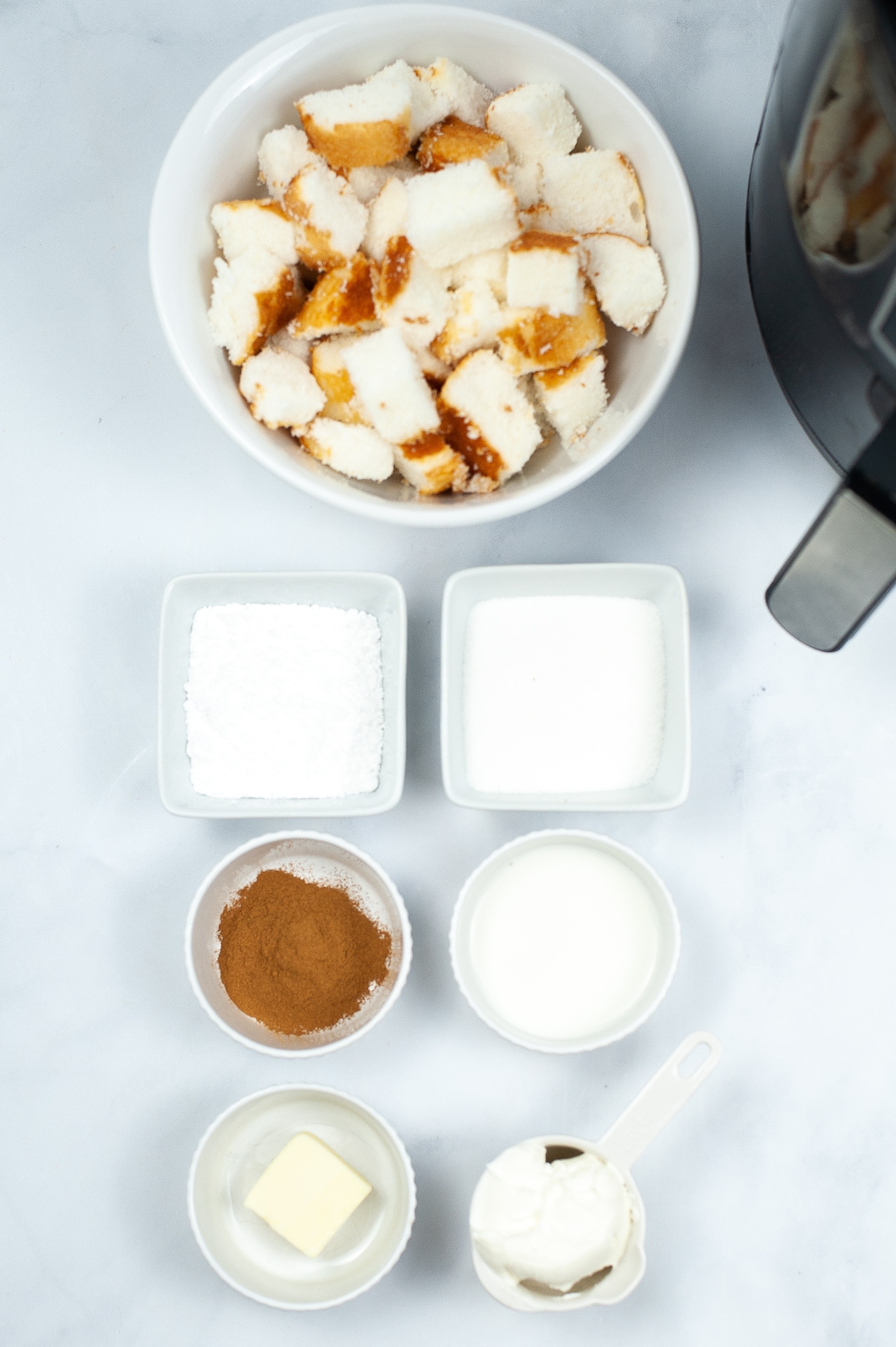 ingredients needed to make air fryer churro bites, each in a separate bowl, on a countertop