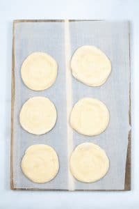 six crescent roll circles on a piece of parchment paper