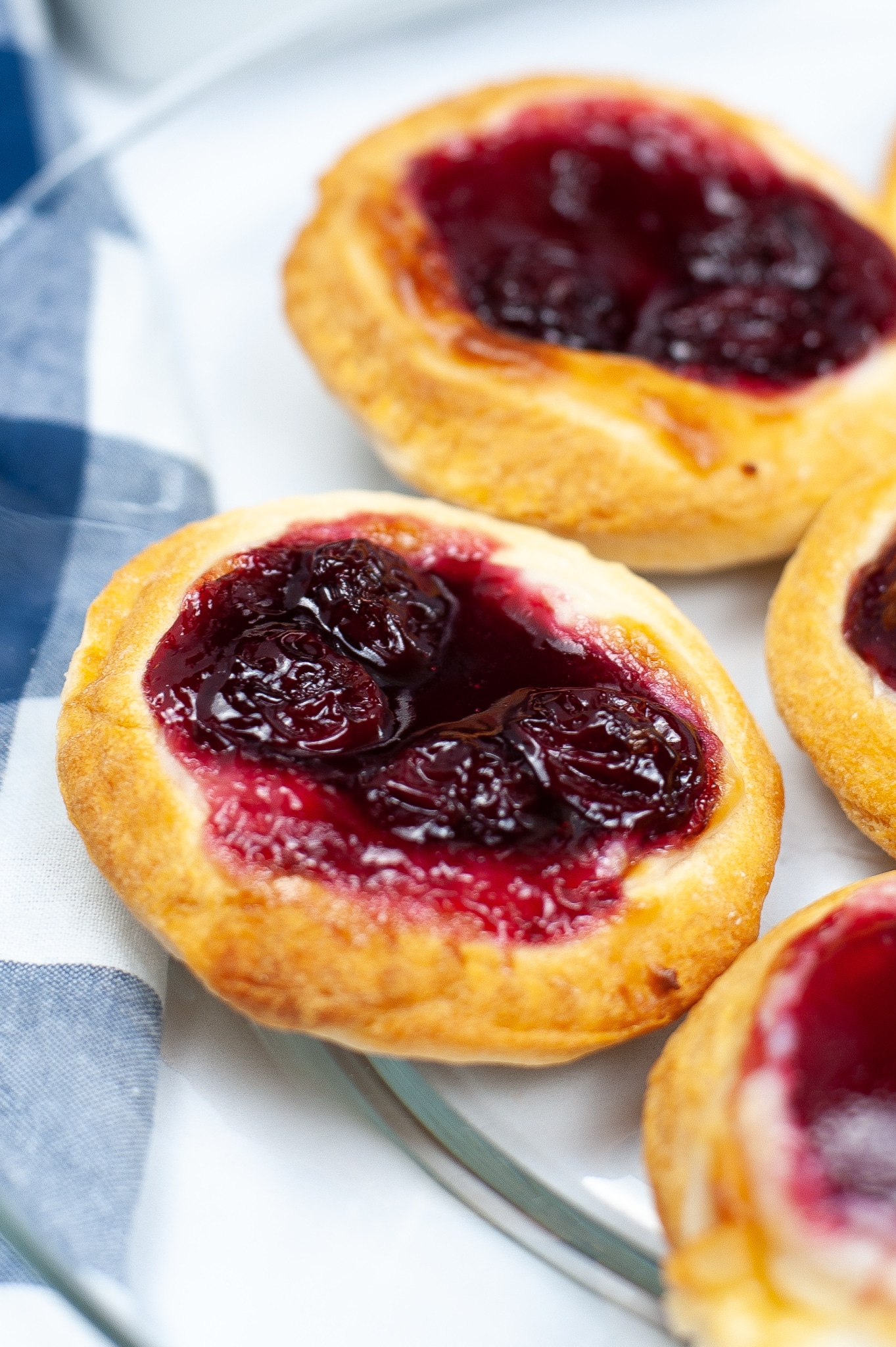 round cherry and cheese danishes next to a blue and white checked towel