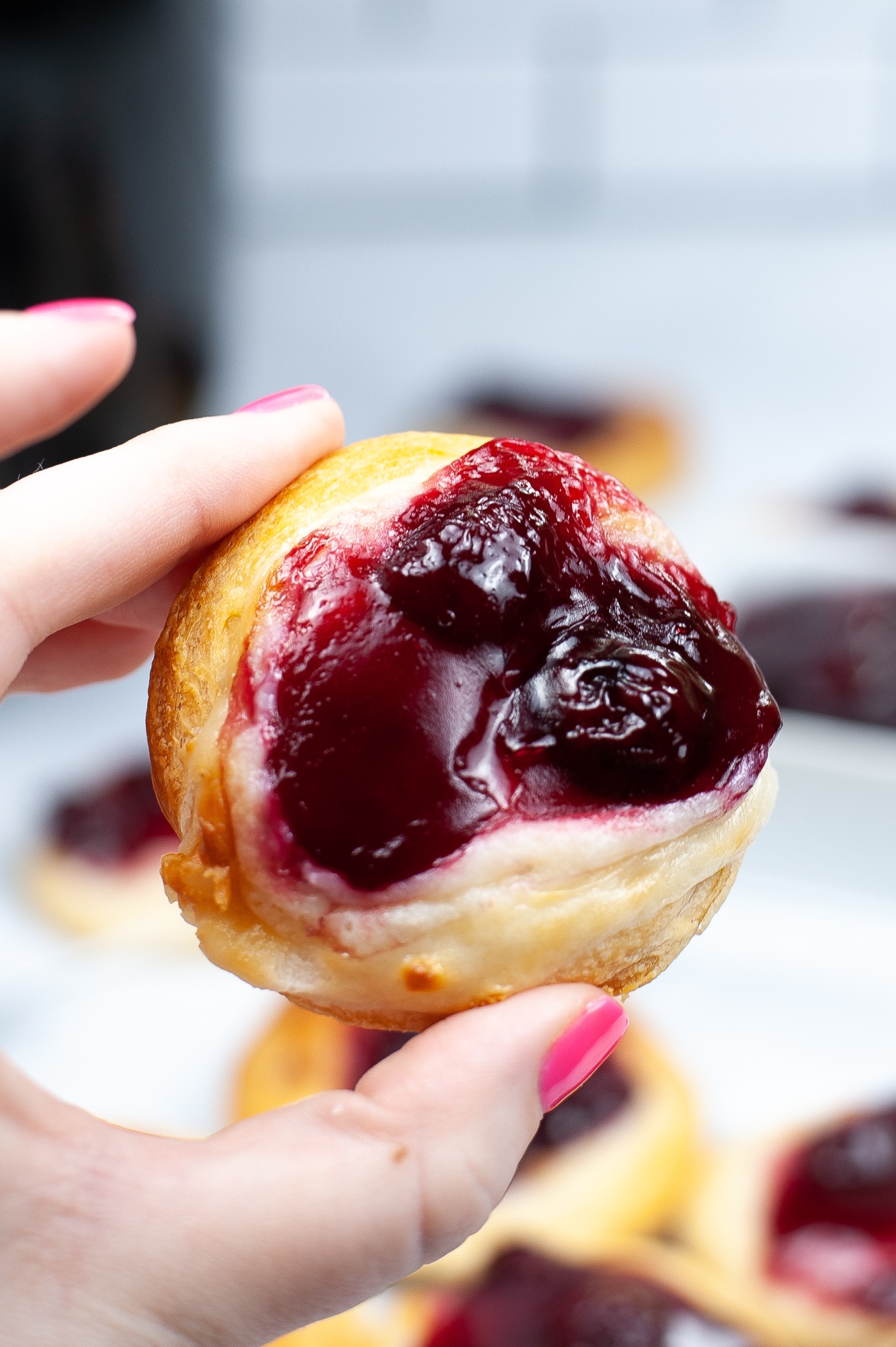 a hand holding a cherry danish