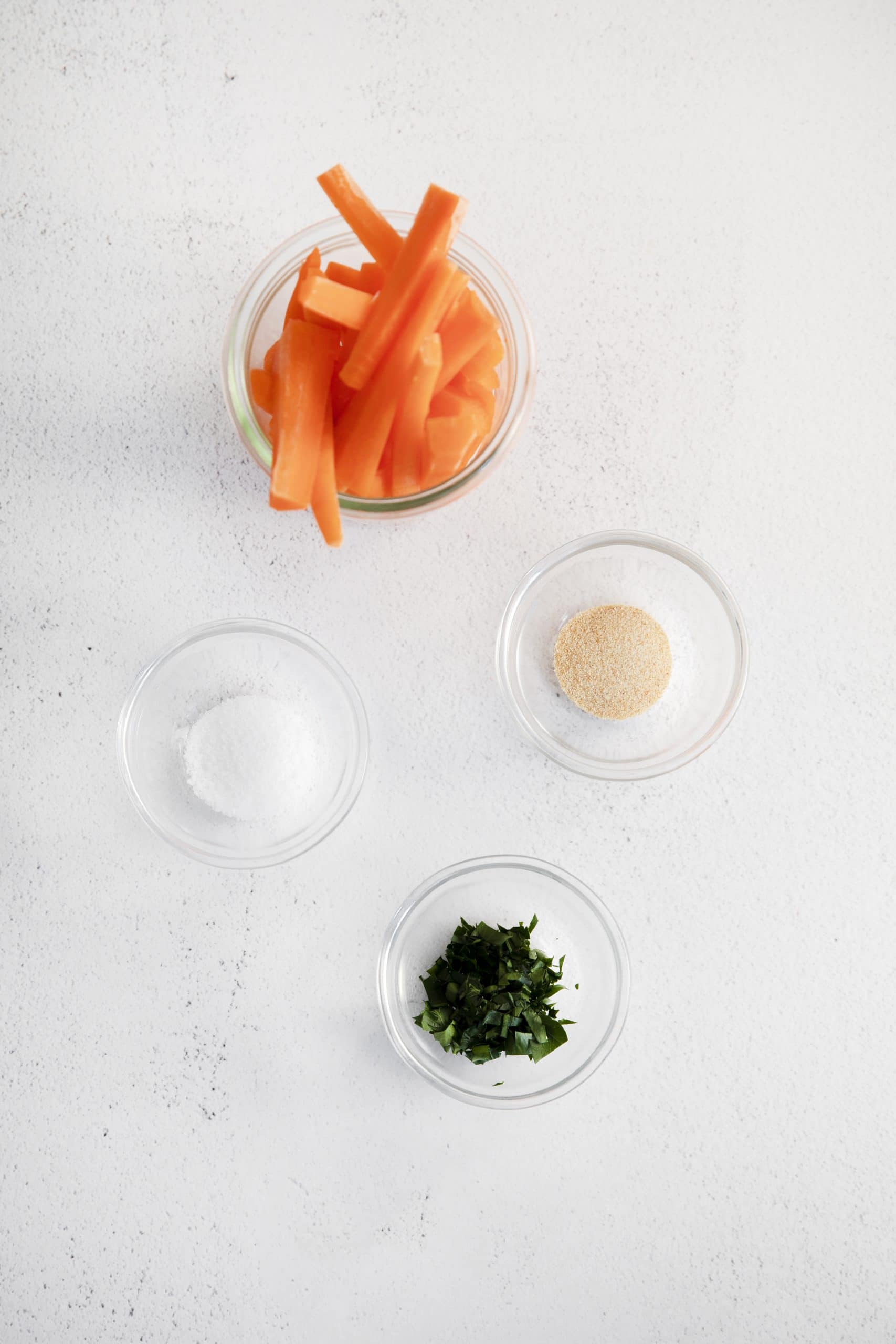 Ingredients for air fryer carrot fries, each in separate dishes on a countertop