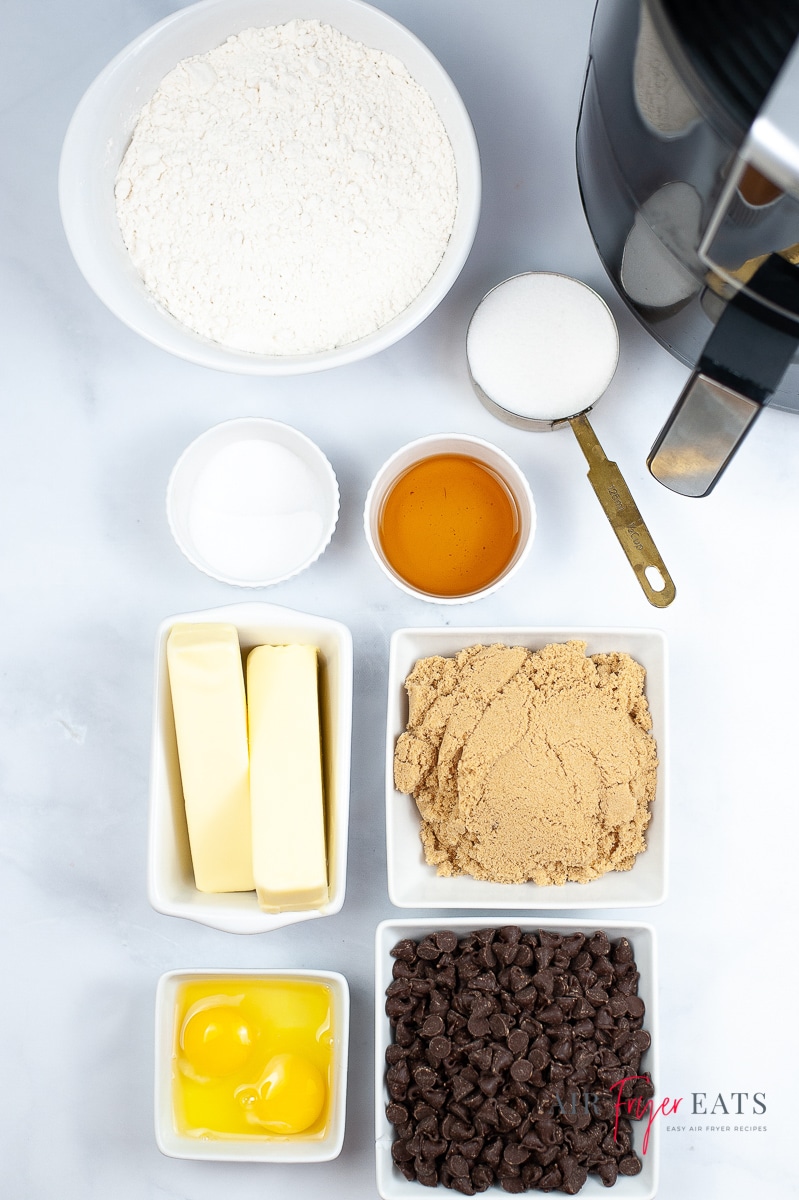 Ingredients for air fryer chocolate chip cookies, each in a separate bowl, next to an air fryer