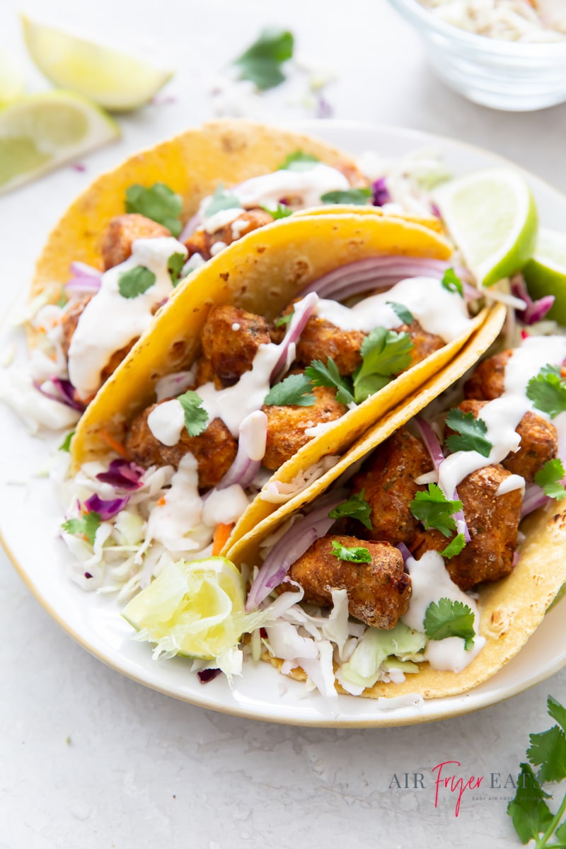 corn tortilla tacos stuffed with air fryer fish, garlic lime crema, cabbage and cilantro.