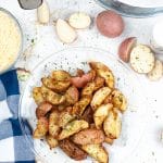 Overhead photo of air fryer roasted red potatoes on a glass plate, with other ingredients scattered around the plate