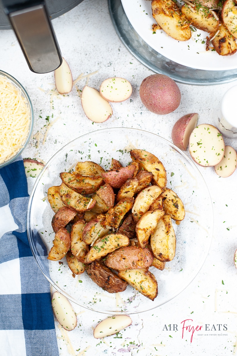 Overhead photo of air fryer roasted red potatoes on a glass plate, with other ingredients scattered around the plate