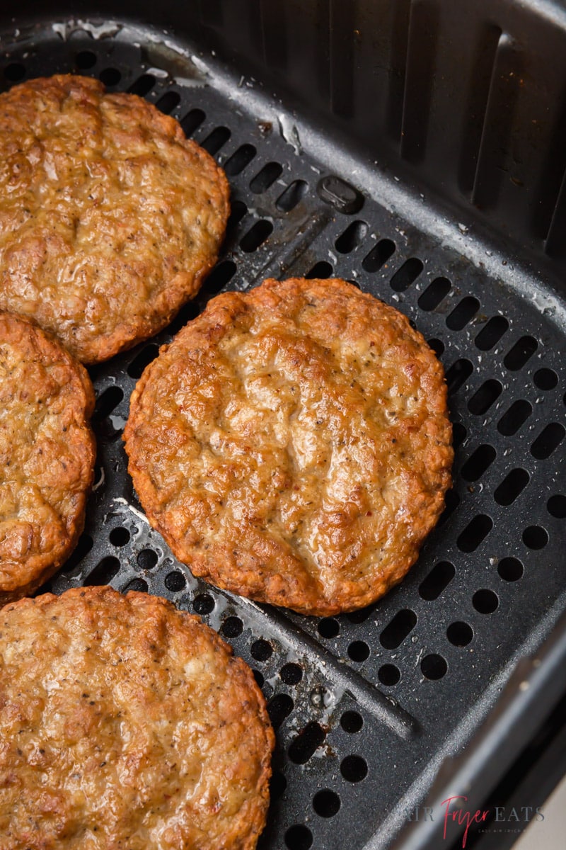 cooked sausage patties in a black air fryer basket. 