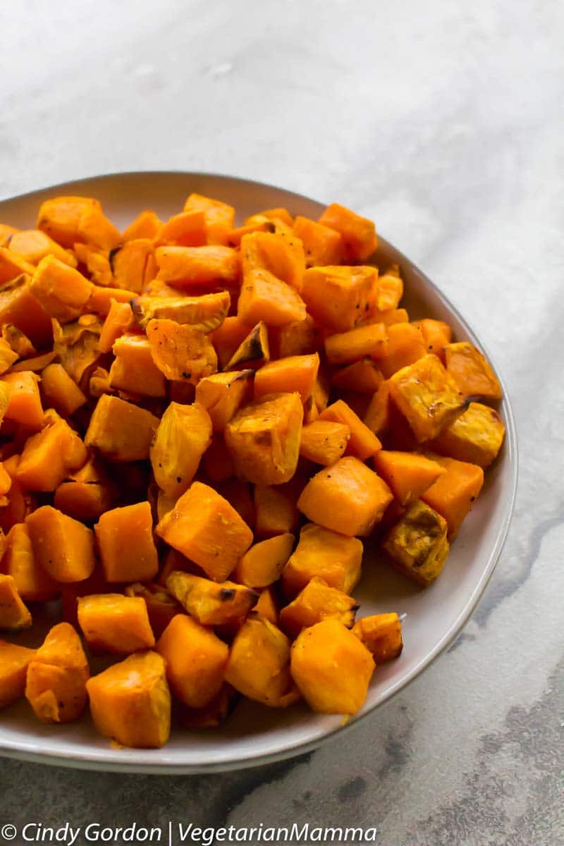 An off-white bowl of roasted cubed sweet potatoes