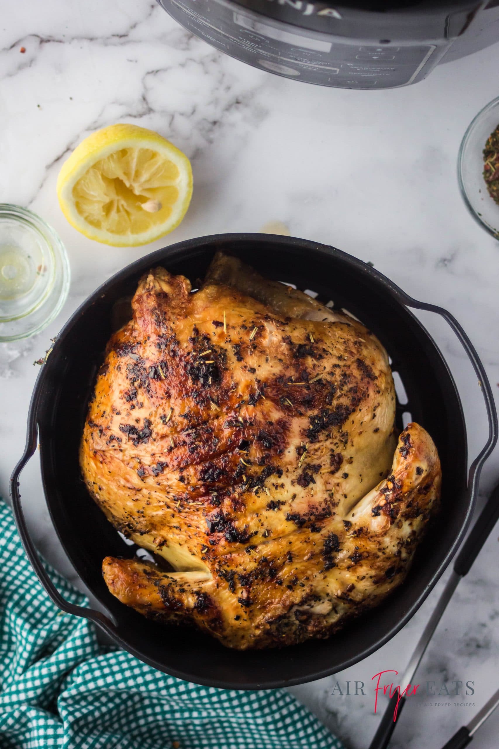 A whole air fryer chicken in a black pan.