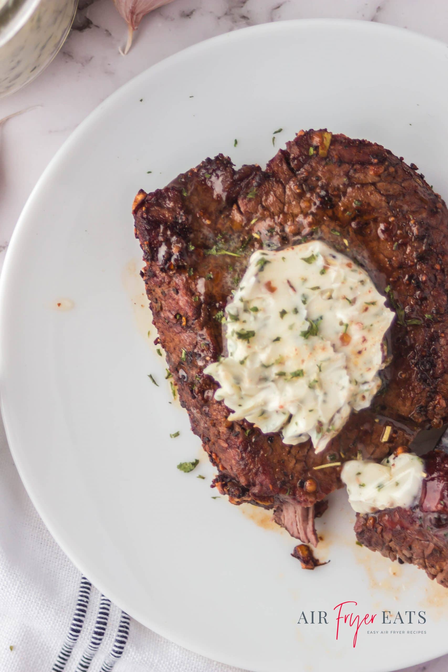 top down view of a ninja foodi cooked steak with herb butter on top.