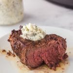 a thick steak, cut in half to show medium cooked temperature, with garlic butter topping.