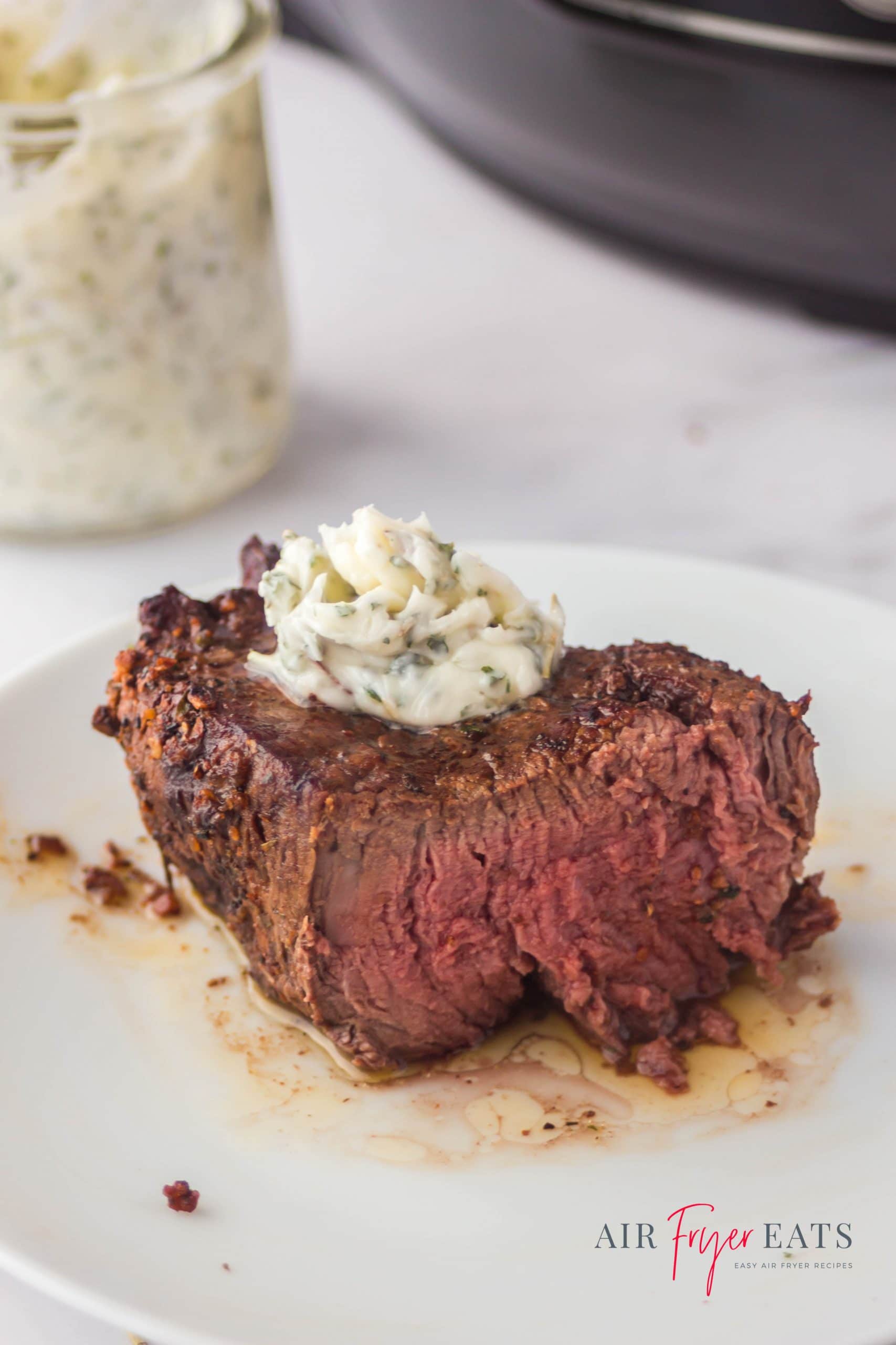 a thick steak, cut in half to show medium cooked temperature, with garlic butter topping.