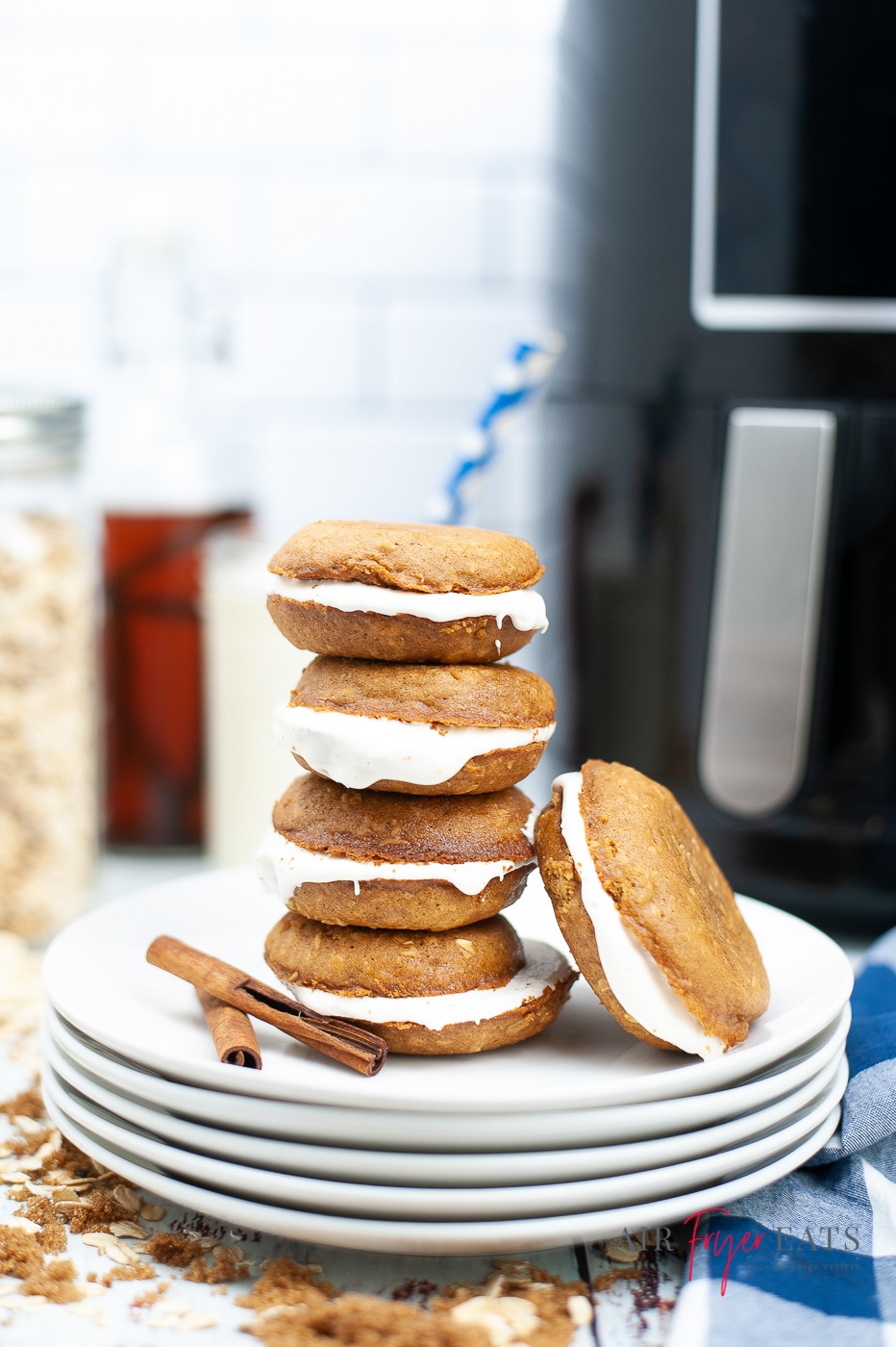 5 white plates stacked on top of each other with 5 oatmeal creme pies on top. black air fryer in background