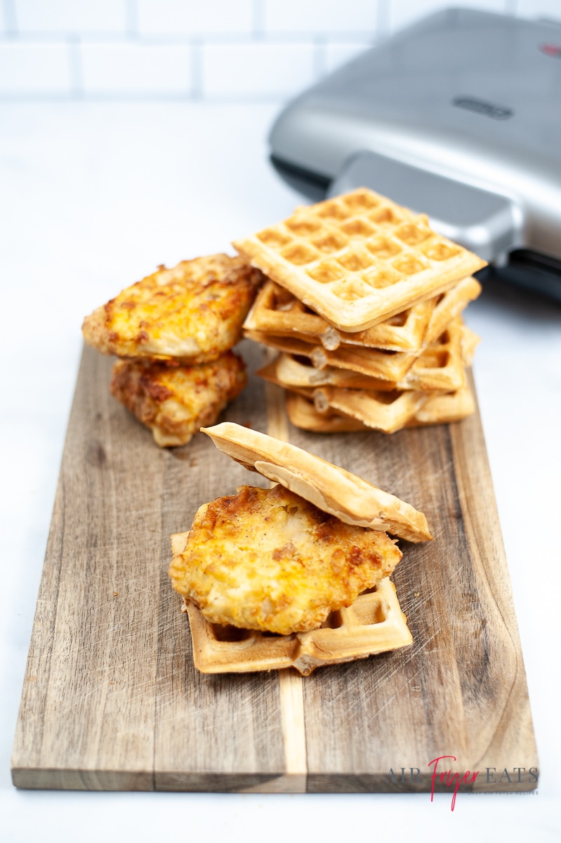 a wooden cutting board with air fryer chicken fillets and square waffles