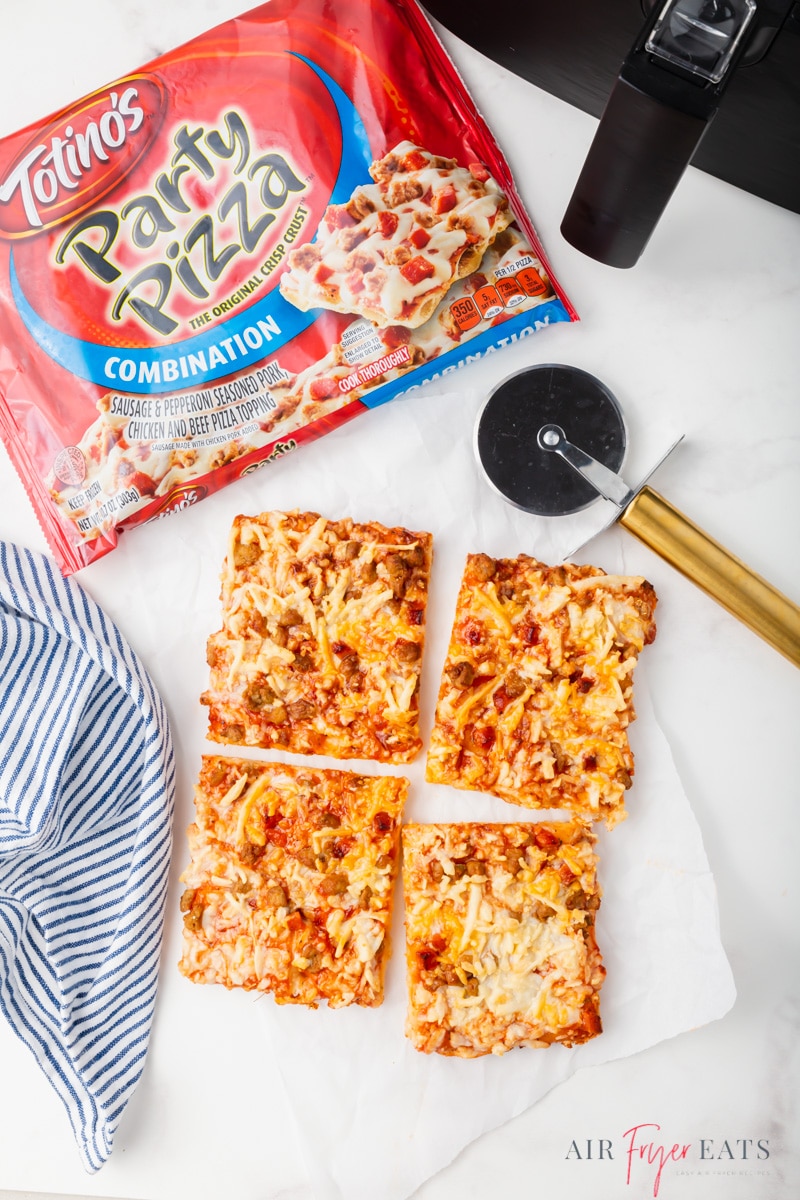 Overhead shot of a Totino's pizza cut into 4 squares with a pizza wheel and packaging