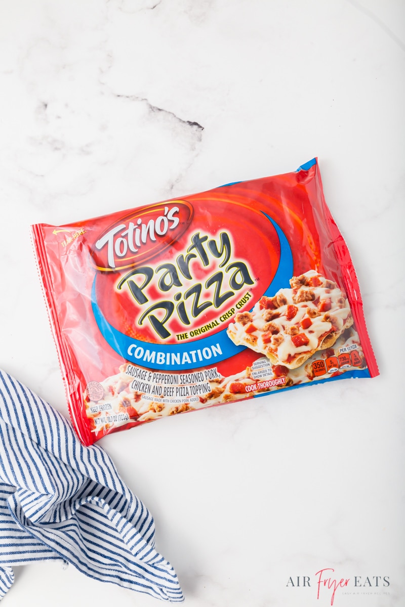 A Totino's combination frozen party pizza in the wrapper on the countertop