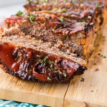 close up view of a meatloaf cooked in an air fryer with a crunchy top, sliced on a cutting board