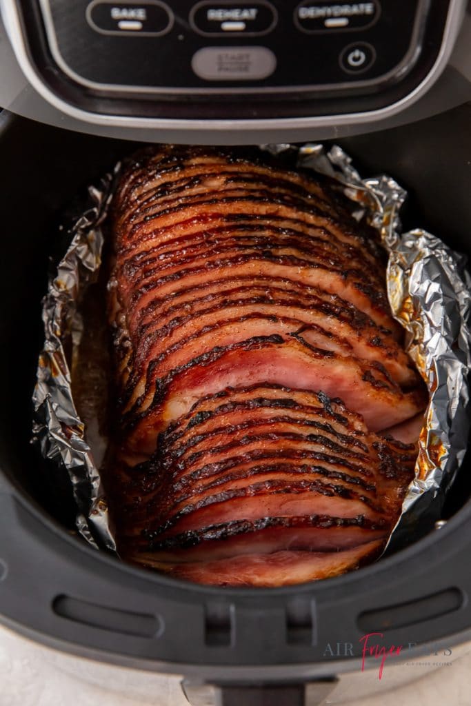 ham on top of foil in air fryer in a black air fryer basket
