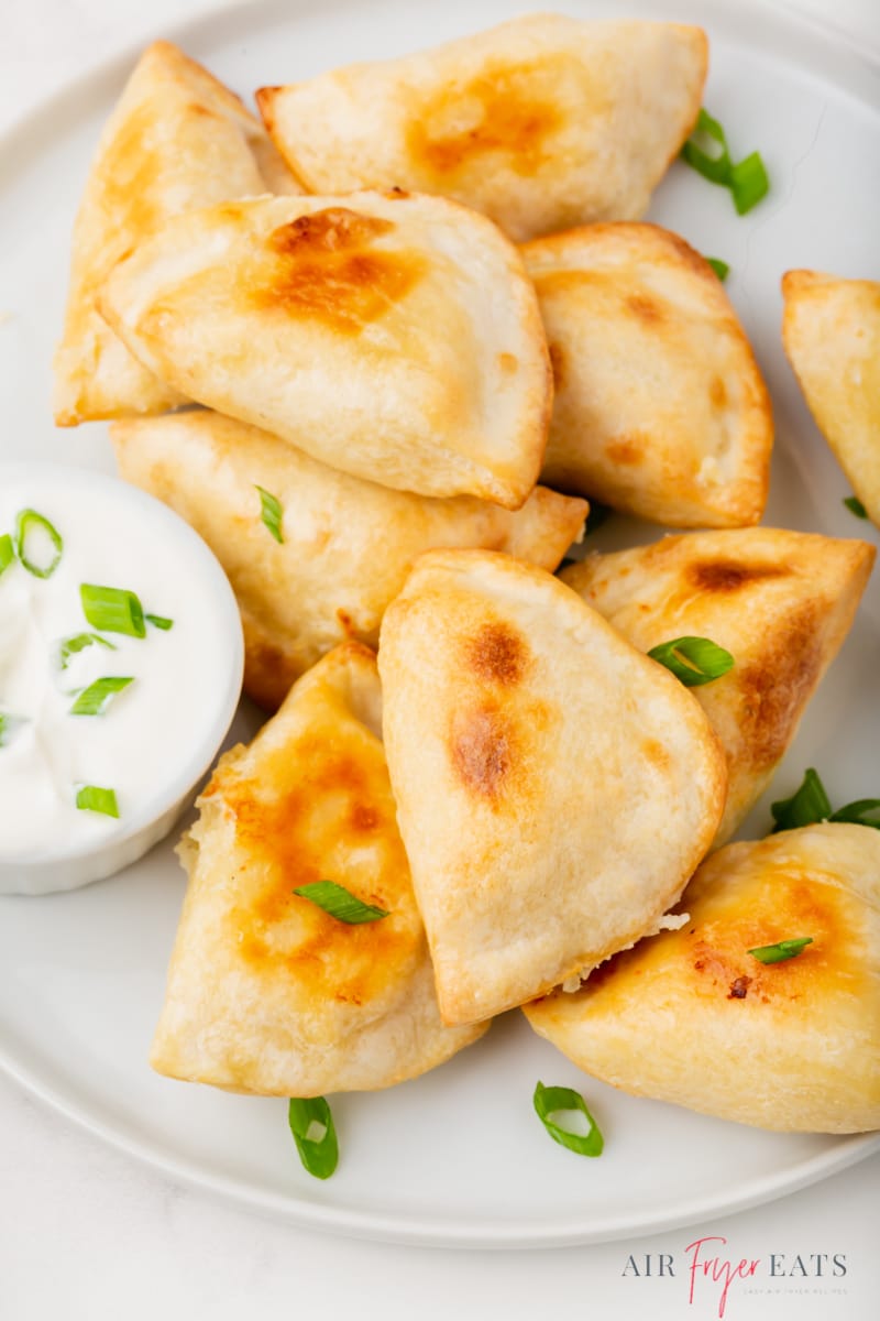  frozen pierogies that were cooked in the air fryer on a plate with a side of creamy dipping sauce