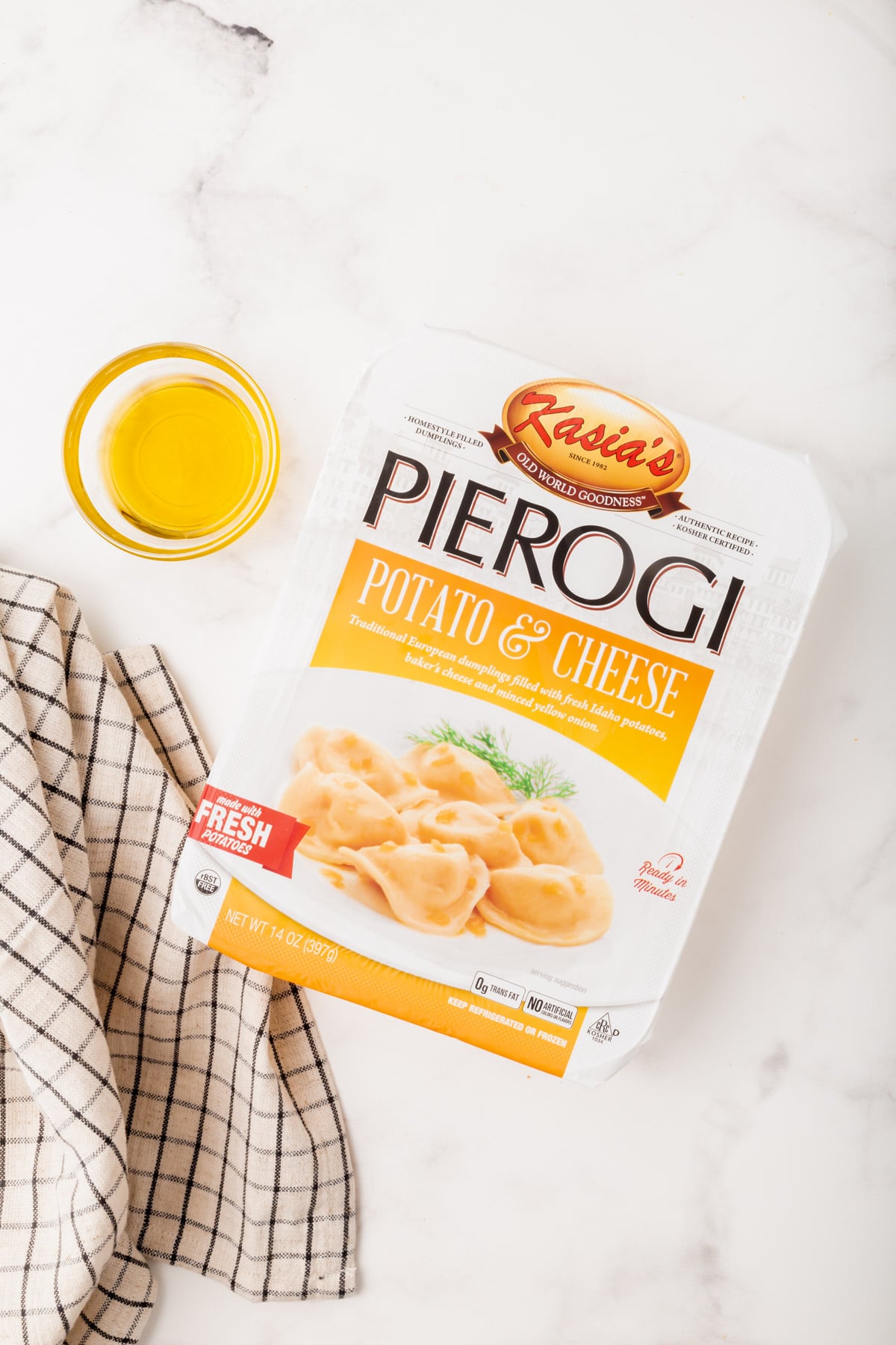a box of frozen pierogies and a glass bowl full of olive oil on the counter